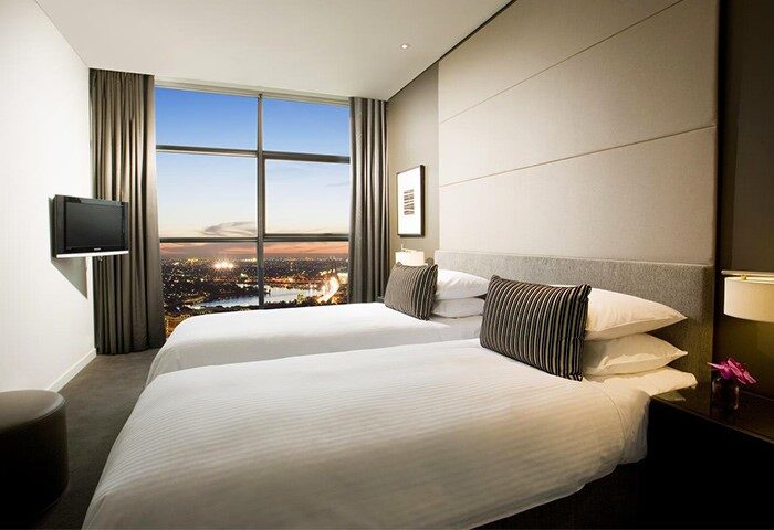 Fraser Suites Sydney gay-friendly hotel room. Twin beds face a large window with a city view. Modern decor in this Sydney gay travel hotel.