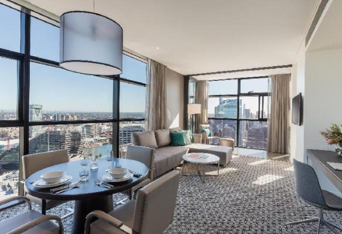 Fraser Suites Sydney: Gay-friendly hotel room with city view. Dining table, sofa, and desk in a modern suite. Great for gay travel in Sydney.