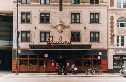 Freehand Chicago, a gay-friendly hotel. Exterior view of the hotel entrance with people, luggage, and bicycles on the sidewalk in Chicago.