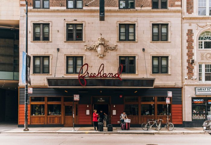Freehand Chicago, a gay-friendly hotel. Exterior view of the hotel entrance with people, luggage, and bicycles on the sidewalk in Chicago.
