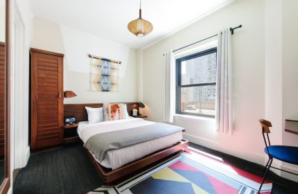 Freehand Chicago hotel room. Gay-friendly travel. Queen bed, wood furniture, colorful rug, city view. Modern decor. Chicago hotel.