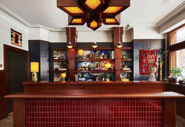 Freehand Chicago gay-friendly hotel lobby. Wood reception desk with red tiles, shelves with decor, and a unique light fixture.