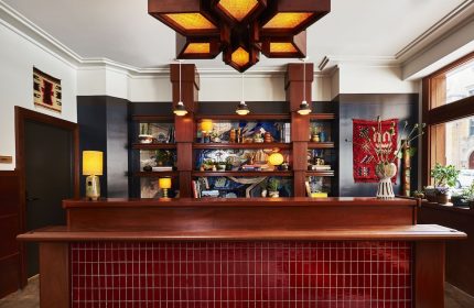 Freehand Chicago gay-friendly hotel lobby. Wood reception desk with red tiles, shelves with decor, and a unique light fixture.