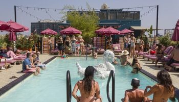 Rooftop pool scene at Gay-Friendly Freehand Los Angeles Hotel. People swimming, lounging, and enjoying the sun. Fun, inclusive travel.
