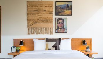 Freehand Los Angeles hotel room with bed, woven wall hanging, and paintings. A gay-friendly travel destination with unique decor.
