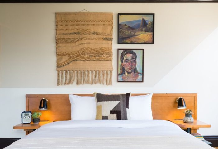 Freehand Los Angeles hotel room with bed, woven wall hanging, and paintings. A gay-friendly travel destination with unique decor.