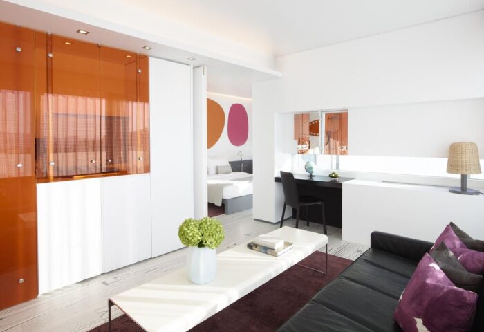 Fresh Hotel interior. Gay-friendly hotel room with a modern design, featuring a work desk, living area, and bedroom. Travel advice.