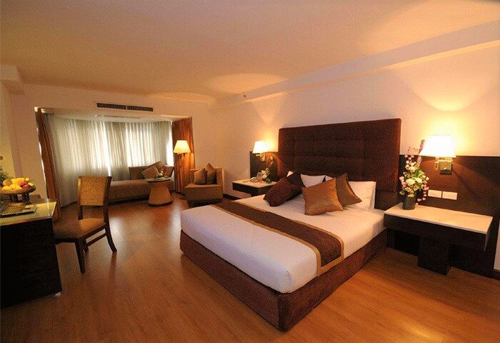 Furama Chiang Mai hotel room. Gay-friendly hotel with a bed, couch, chair, desk, and wooden floors. Modern design for gay men travelers.