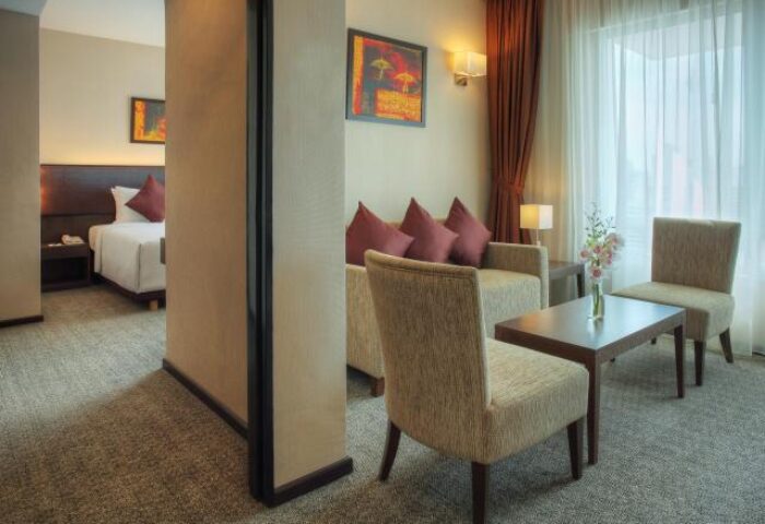 Furama Hotel Bukit Bintang suite. Gay-friendly hotel room featuring a bed, sitting area with sofa, chairs, and table. Modern, comfortable design.