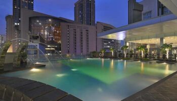 Furama Hotel Bukit Bintang pool at night. Gay-friendly hotel in Kuala Lumpur with rooftop pool and city views. Luxury travel for gay men.
