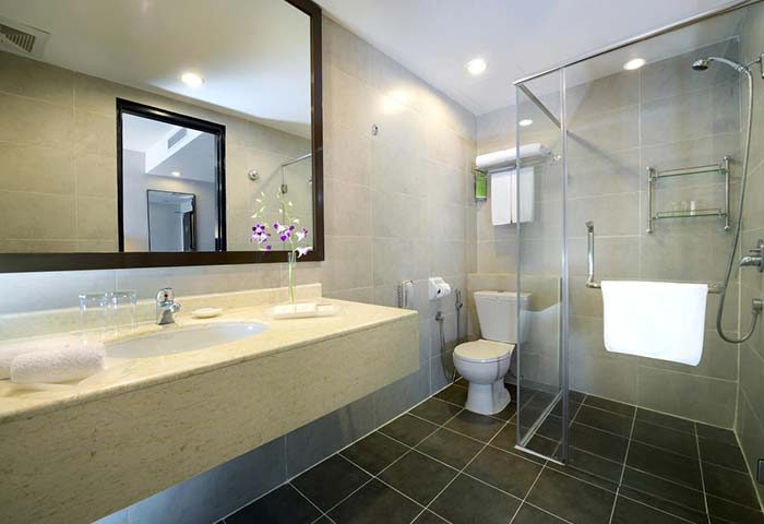 Bathroom at Furama Hotel Bukit Bintang. Modern design with shower stall, toilet, sink, and large mirror. Gay-friendly hotel in Kuala Lumpur.