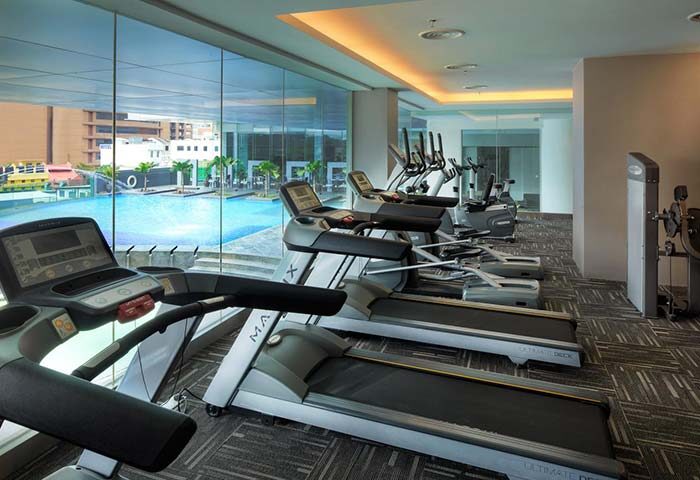 Furama Hotel Bukit Bintang gym with treadmills, exercise bikes, and weights. Pool view. Gay-friendly hotel fitness center for gay travelers.