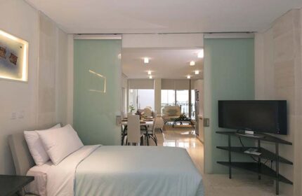 FuramaXclusive Ocean Beach Hotel Seminyak suite. Gay-friendly hotel room with bed, TV, dining area, and balcony. Modern design.