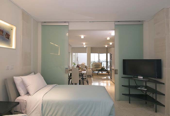 FuramaXclusive Ocean Beach Hotel Seminyak suite. Gay-friendly hotel room with bed, TV, dining area, and balcony. Modern design.