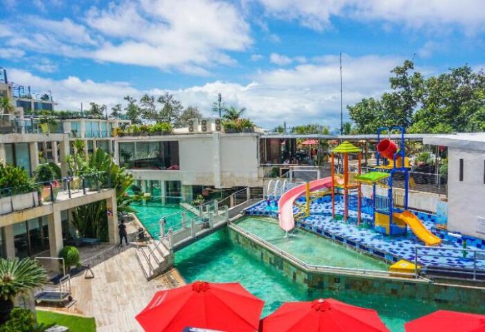 FuramaXclusive Ocean Beach Hotel Seminyak: Gay-friendly hotel with pool, kids' water park, and modern architecture under a blue sky.