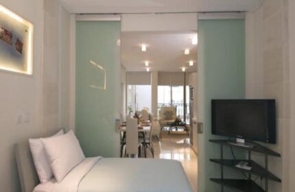 FuramaXclusive Ocean Beach Hotel Seminyak suite. Gay-friendly hotel room with bed, TV, and dining area. Modern design in Seminyak, Bali.