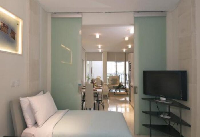FuramaXclusive Ocean Beach Hotel Seminyak suite. Gay-friendly hotel room with bed, TV, and dining area. Modern design in Seminyak, Bali.