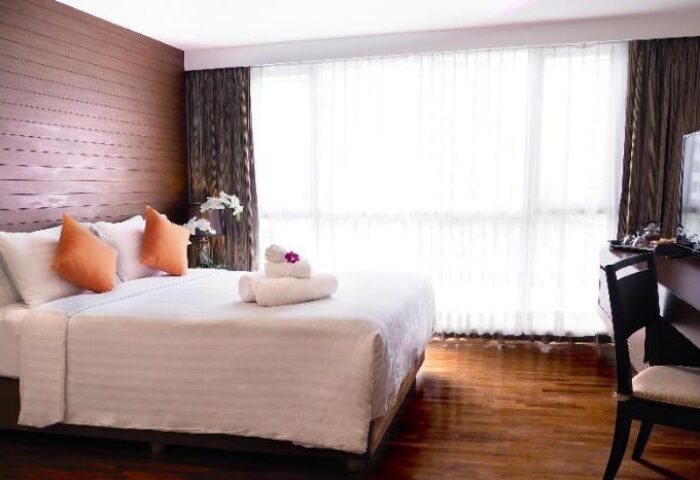 FuramaXclusive Sathorn Hotel Bangkok room. Gay-friendly hotel with bed, pillows, towels, and desk. Modern design in Sathorn, Bangkok.