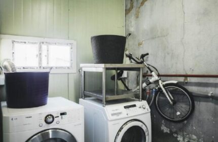 Laundry area at G Guesthouse Itaewon in Seoul, a gay-friendly hotel. Washing machines, laundry baskets, and a bicycle on the wall.
