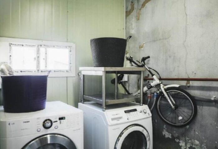 Laundry area at G Guesthouse Itaewon in Seoul, a gay-friendly hotel. Washing machines, laundry baskets, and a bicycle on the wall.