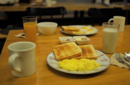 Breakfast at G Guesthouse Itaewon in Seoul, a gay-friendly hotel. Toast, scrambled eggs, juice, milk, and coffee on a wooden table.