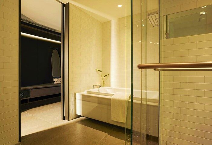 GLAD Yeouido gay-friendly hotel bathroom. Bathtub with glass shower. Closet with ironing board. Modern design. Gay travel advice.