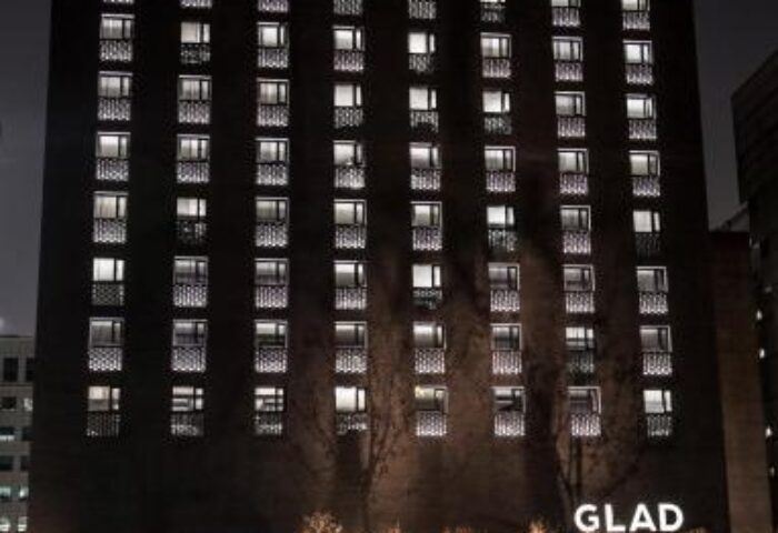 Night view of GLAD Yeouido, a gay-friendly hotel in Seoul. Modern building with illuminated windows. Ideal for gay travelers seeking comfort.