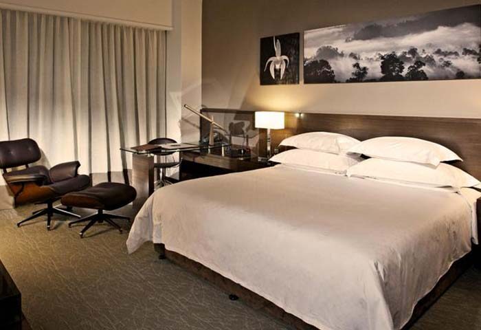 GTower Hotel's gay-friendly room: A luxurious bedroom with a large bed, desk, and stylish chair. Modern decor and comfortable for gay travelers.