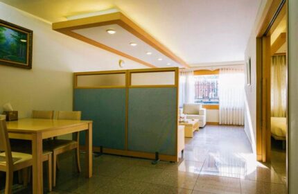 GV Residence gay-friendly hotel room. Dining area with table and chairs, living area with sofa, and bedroom visible through doorway.