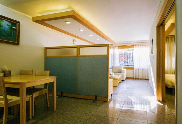 GV Residence gay-friendly hotel room. Dining area with table and chairs, living area with sofa, and bedroom visible through doorway.