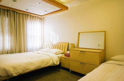 GV Residence gay-friendly hotel room. Features twin beds, light wood furniture, and soft lighting. Comfortable accommodations for gay travelers.