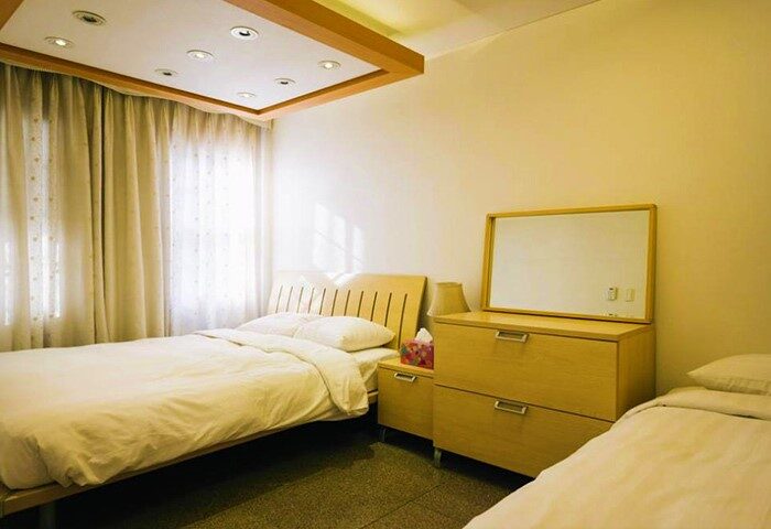 GV Residence gay-friendly hotel room. Features twin beds, light wood furniture, and soft lighting. Comfortable accommodations for gay travelers.