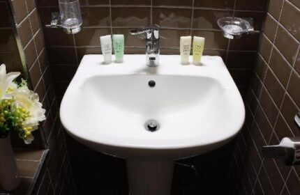 GV Residence gay-friendly hotel bathroom sink. Modern design, clean white basin, and brown tiled walls. Ideal for gay men's travel.