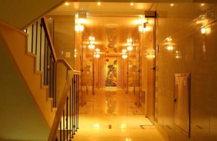 GV Residence, a gay-friendly hotel: Hallway view with stairs. Golden walls and floor, illuminated by sconces, lead to an ornate artwork.