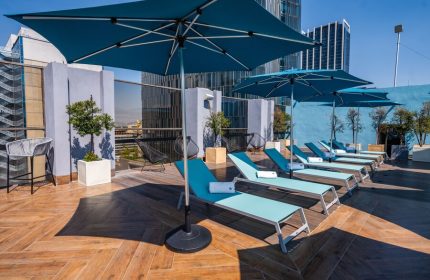 Galeria Plaza Reforma gay-friendly hotel rooftop pool. Blue umbrellas shade lounge chairs on wood deck. Modern Mexico City hotel for gay travelers.