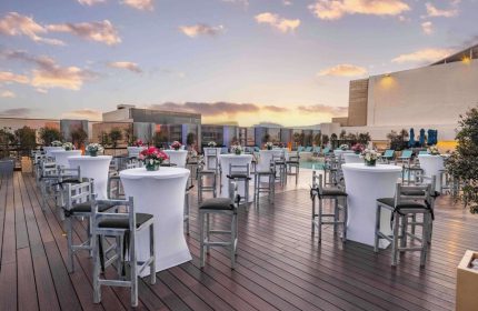 Galeria Plaza Reforma gay-friendly hotel rooftop. Tables and chairs are set up for an event by the pool at sunset. Gay travel advice.