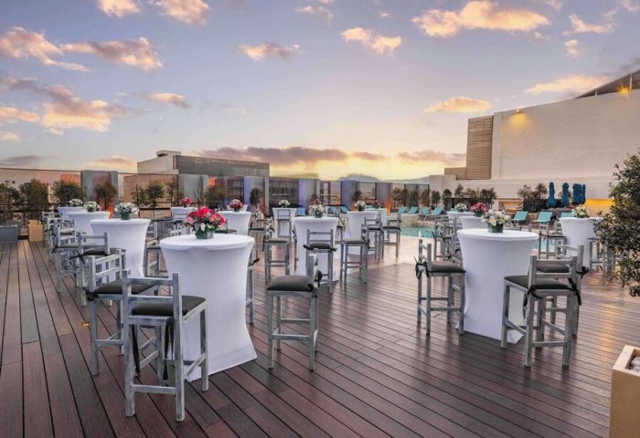 Galeria Plaza Reforma gay-friendly hotel rooftop. Tables and chairs are set up for an event by the pool at sunset. Gay travel advice.