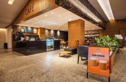 Galeria Plaza Reforma's café. Gay-friendly hotel with Starbucks. Latte con Amor sign, bar, and seating. Modern design, ideal for gay travelers.