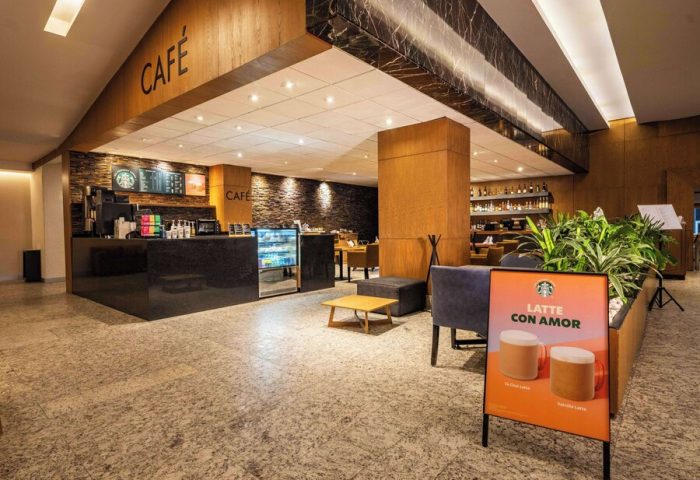 Galeria Plaza Reforma's café. Gay-friendly hotel with Starbucks. Latte con Amor sign, bar, and seating. Modern design, ideal for gay travelers.