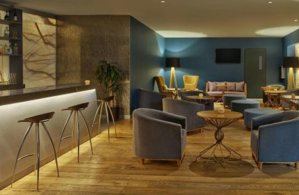 Galeria Plaza Reforma gay-friendly hotel bar. Lounge area with chairs, tables, and bar stools. Modern interior design in Mexico City.