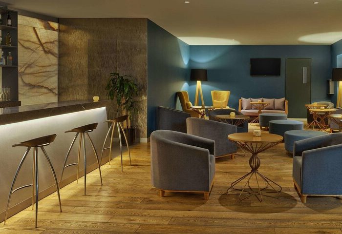 Galeria Plaza Reforma gay-friendly hotel bar. Lounge area with chairs, tables, and bar stools. Modern interior design in Mexico City.