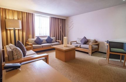 Galeria Plaza Reforma gay-friendly hotel suite. Living area with couches, pillows, tables, lamp, and decor. Modern design in Mexico City.