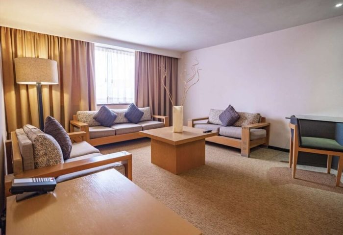 Galeria Plaza Reforma gay-friendly hotel suite. Living area with couches, pillows, tables, lamp, and decor. Modern design in Mexico City.