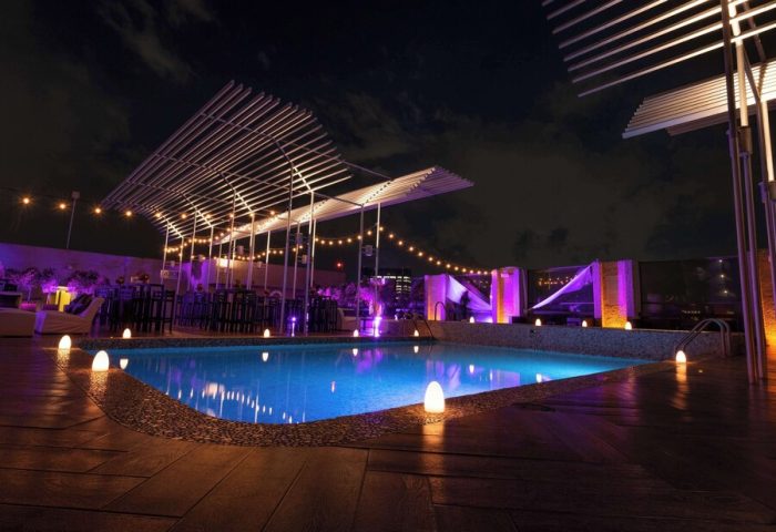 Galeria Plaza Reforma gay-friendly hotel pool at night. Rooftop pool with lights, tables, and chairs. A great place for gay men to relax and enjoy.