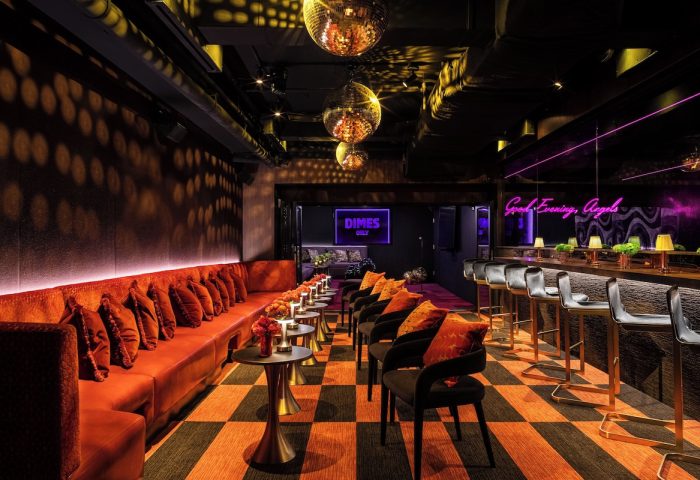 Gansevoort Meatpacking NYC gay-friendly hotel bar interior. Disco balls, plush seating, and neon signage create a vibrant, welcoming atmosphere.