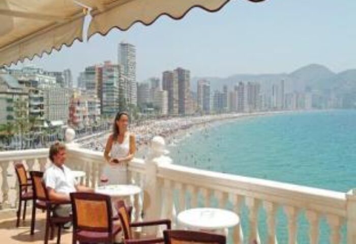 Gastrohotel Boutique RH Canfali's balcony view. Couple enjoying the beach scenery. Gay-friendly hotel in Spain. Coastal city skyline.