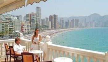 Gastrohotel Boutique RH Canfali's balcony view. Couple enjoying the beach scenery. Gay-friendly hotel in Spain. Coastal city skyline.