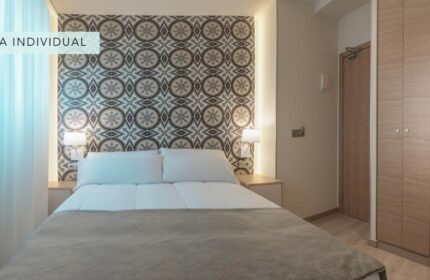 Gastrohotel Boutique RH Canfali room. Gay-friendly hotel featuring a double bed with patterned headboard. Ideal for gay travelers.