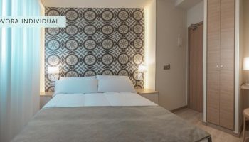 Gastrohotel Boutique RH Canfali room. Gay-friendly hotel featuring a double bed with patterned headboard. Ideal for gay travelers.