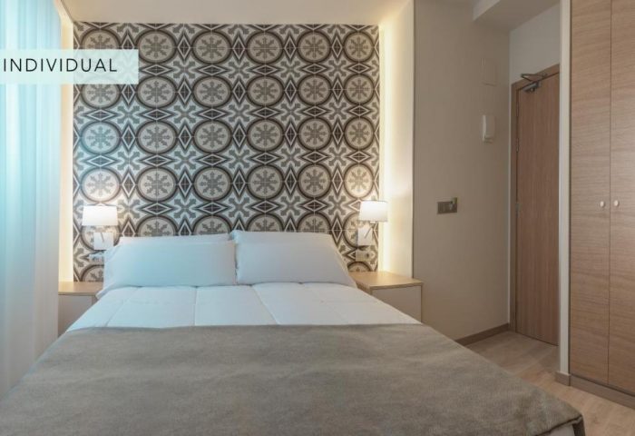 Gastrohotel Boutique RH Canfali room. Gay-friendly hotel featuring a double bed with patterned headboard. Ideal for gay travelers.
